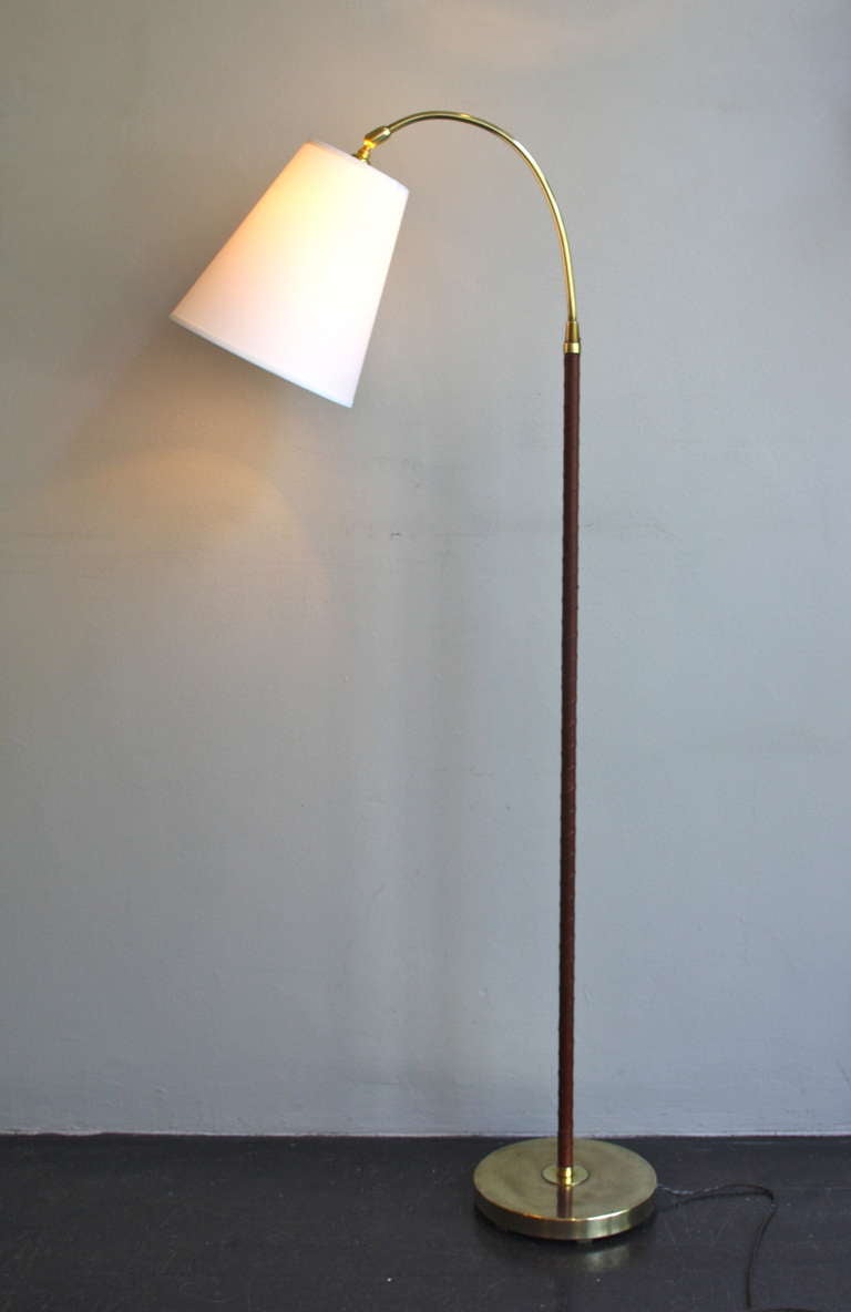 A beautiful Swedish floor lamp with a wonderful cognac leather wrap around the brass stem. a great angled light with adjustable head. It has been rewired for UK and has a new cotton shade. Would look splendid in any household.