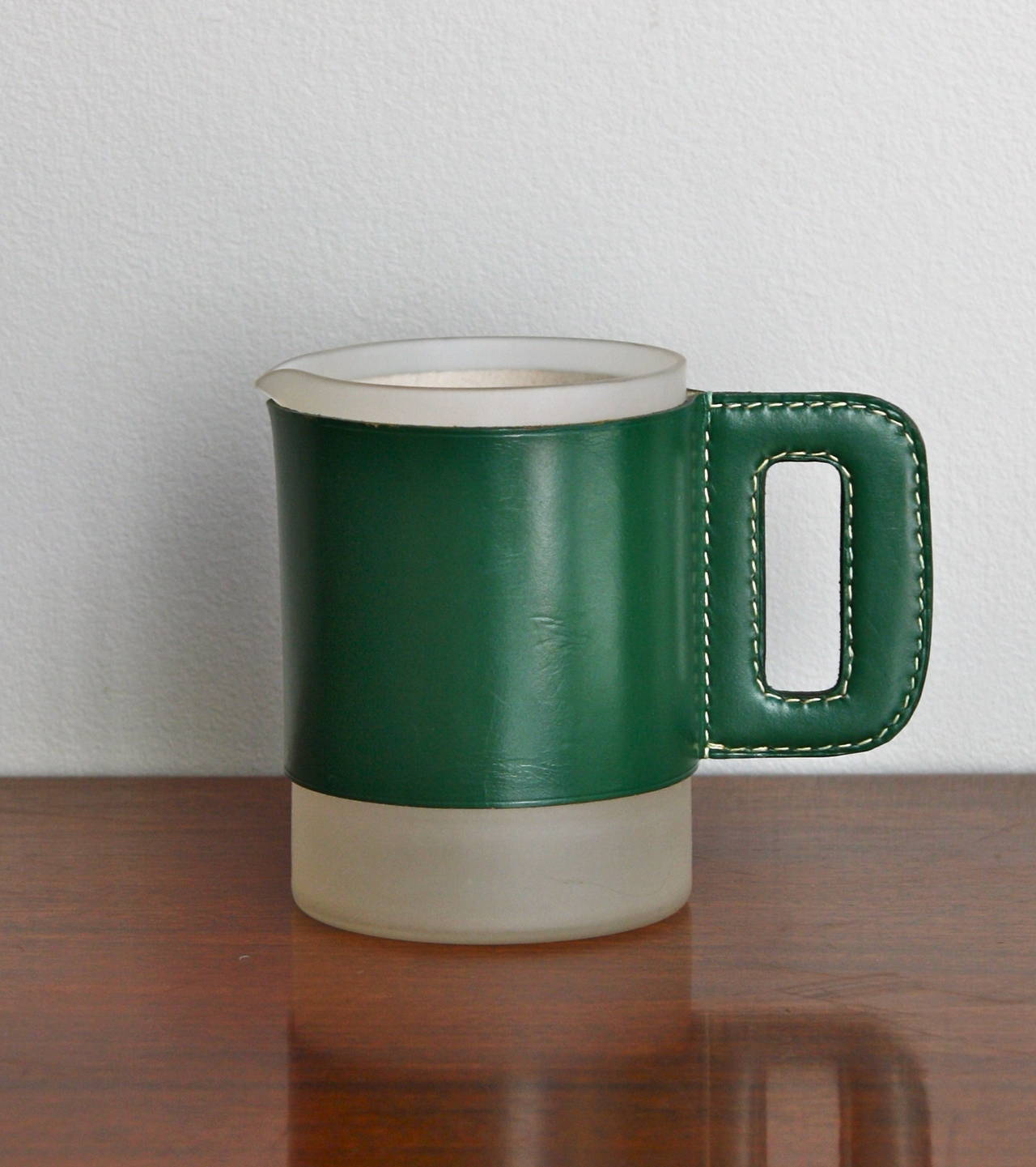 A strong and elegant pitcher by Carl Auböck. A lovely deep green hand-stitched leather covered over an opaque glass lipped beaker. A great example of how Werkstätte Carl Auböck can create lovely honest hand crafted objects. This version with the