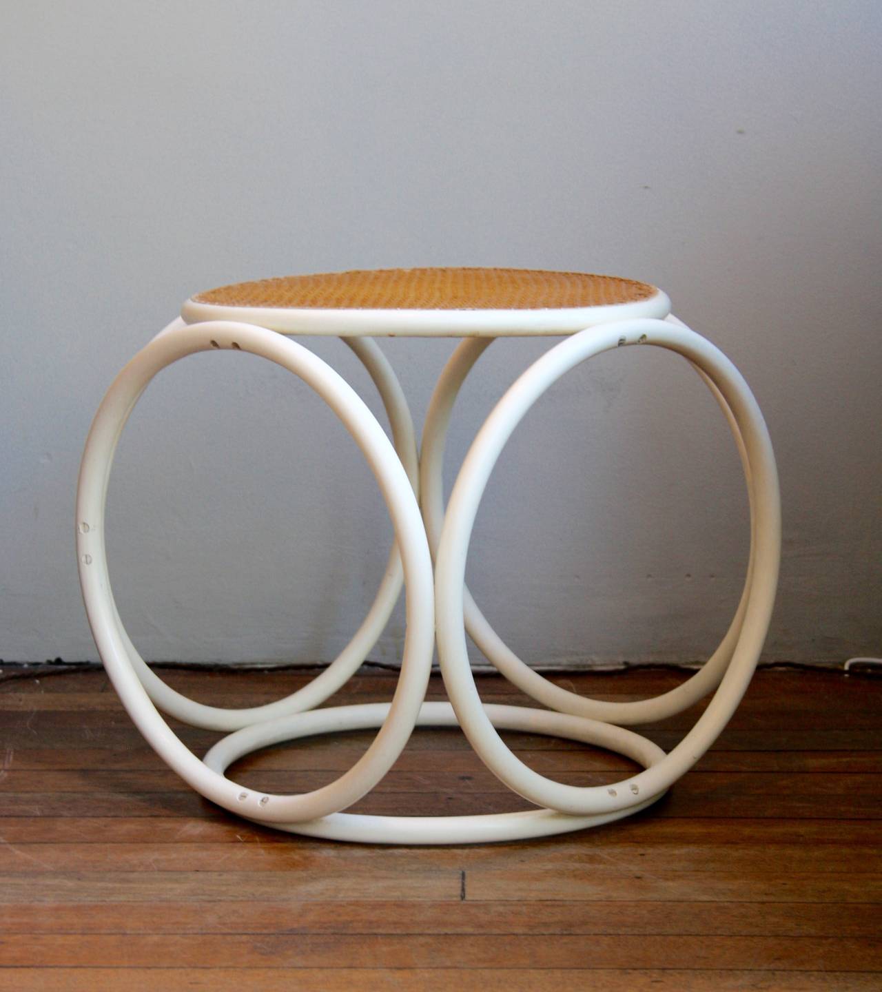 Ottoman in white painted steam bent wood with a cane seat designed by the Austrian pioneer of furniture construction, Michael Thonet.