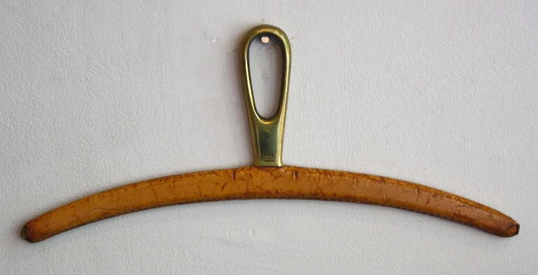 Heavy brass hanger covered in hand stitched leather designed by Carl Aubock and made in his workshop in the 1950s. Rarely seen pieces it is made to work with existing hooks or his wallmounted wardrobes. Great thing