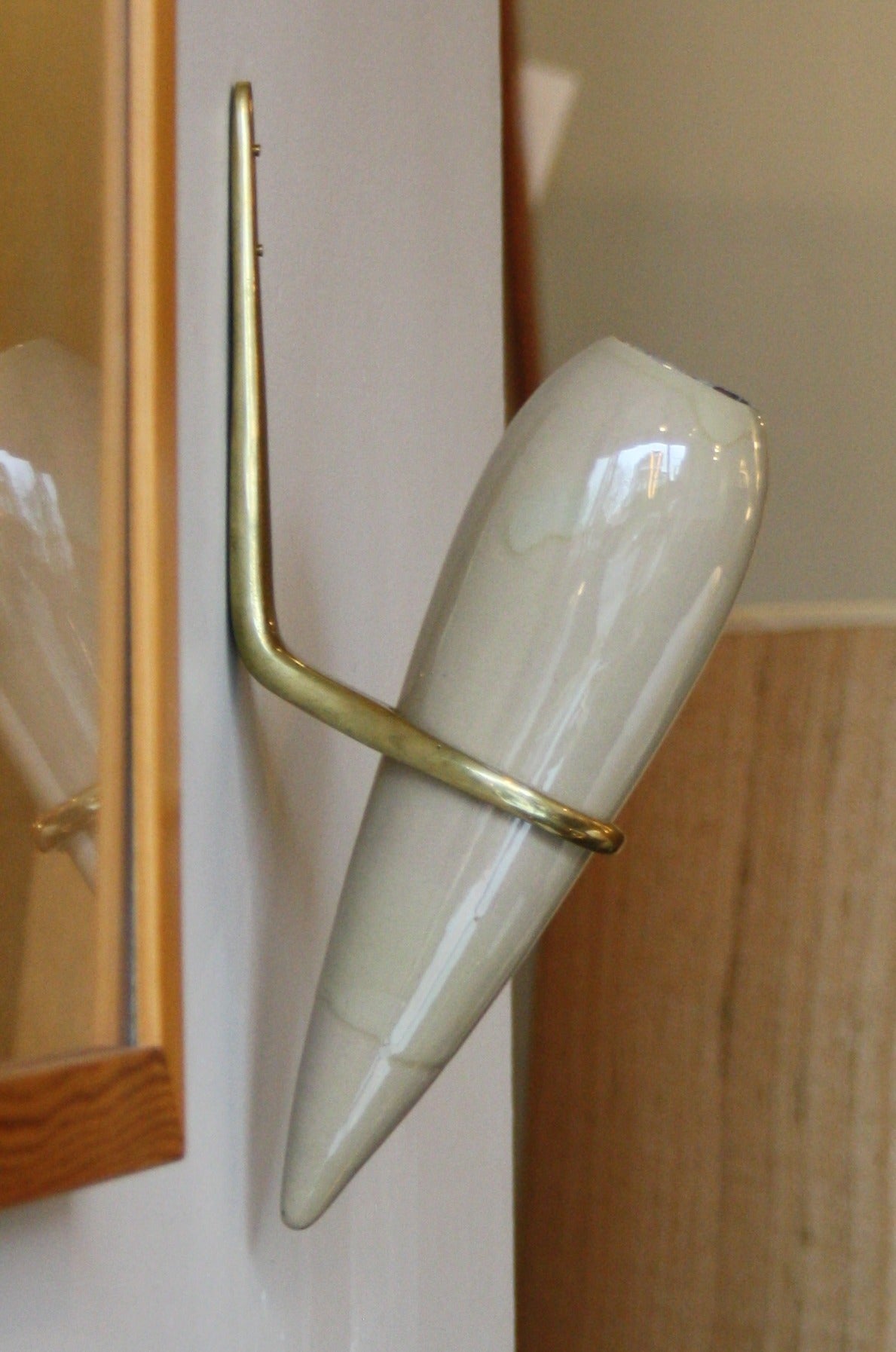 Sculptural vase mounted to the wall with a brass mount. Made by Carl Auböck and Conrad Seidler.