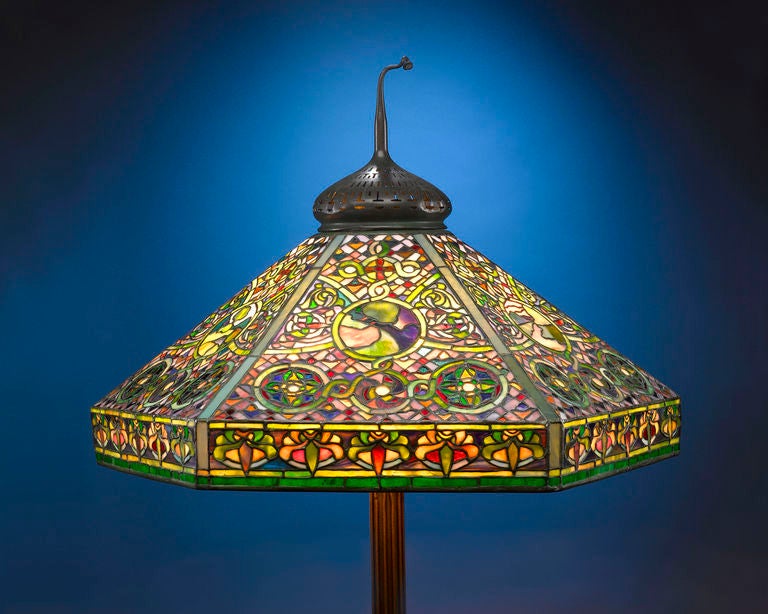 This magnificent Tiffany Studios floor lamp boasts a brilliantly patterned shade depicting landscape scenes and geometric designs. It is a wonderful example that beautifully demonstrates Louis Comfort Tiffany's love of color and fascination with