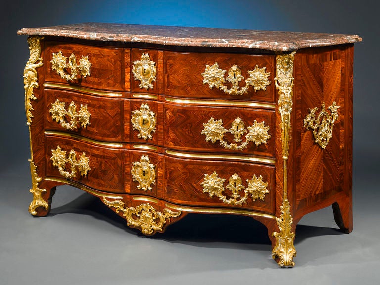 A stunning specimen of the <em>ébéniste’s</em> craft, this important Régence-period <em>arbalète</em> commode, named so for its desirable “crossbow” shape, is veneered in beautiful violet wood and mounted with chiseled mercury-gilded bronze of