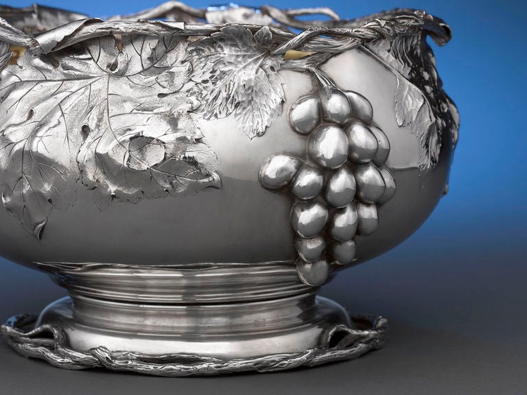 This extraordinary silver punch bowl and ladle by the Frank W. Smith Silver Co. is covered with dramatic, three-dimensional bunches of grapes, detailed leaves, and a pierced vine rim. The ladle features an elegantly gilt bowl. This exquisite design