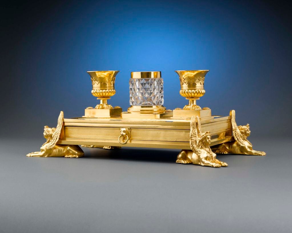 This extremely rare and outstanding Regency ormolu inkstand by the Weeks Museum conceals a mahogany-lined double drawer with impressive lion's head handles in its rectangular base. Four imposing sphinxes support each corner, reflecting the