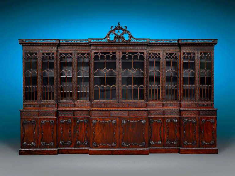 This magnificent Victorian library bookcase is a work of both massive size and monumental beauty. Crafted of Cuban mahogany in the majestic Chippendale Revival style, this dynamic breakfront reaches a width of over 14 feet and a height of over 9