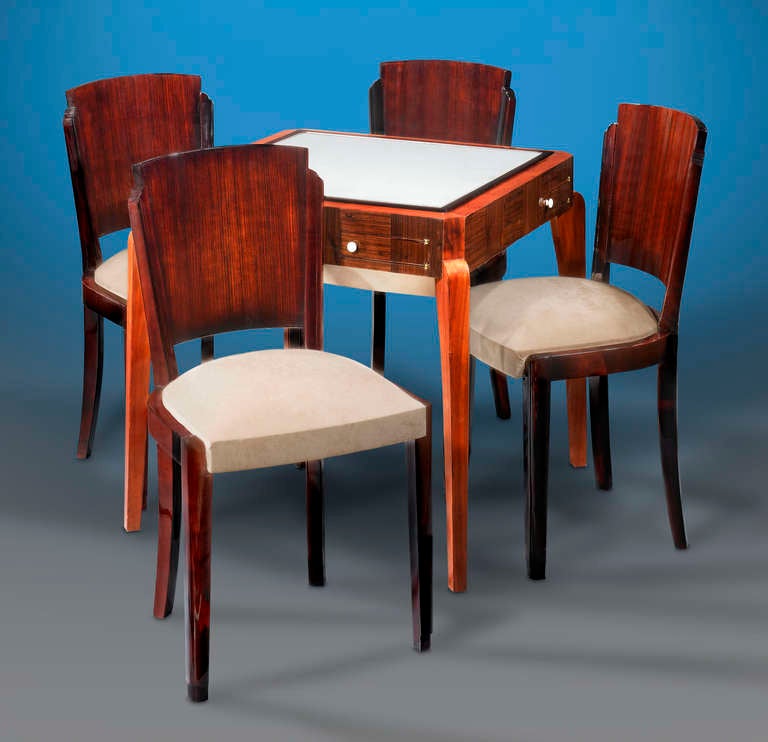 The splendor and elegance of Art Deco design is beautifully illustrated by this fine French table and chairs. Crafted of luxurious rosewood and mahogany, the table boasts a playing surface of soft suede bordered with rare Madagascar ebony. On each