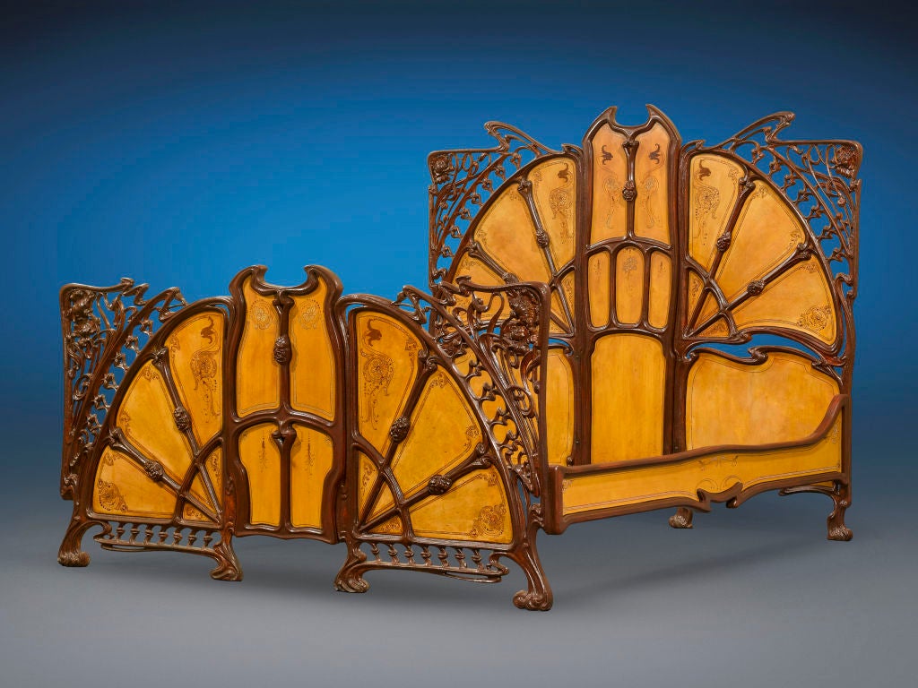 This astounding Art Nouveau bed is a symphony of Belle Époque enchantment. Crafted of cast iron with fitted wood panels, this majestic bed is composed of a headboard, footboard and sides, with flowing lines artfully arranged in a naturalistic fan