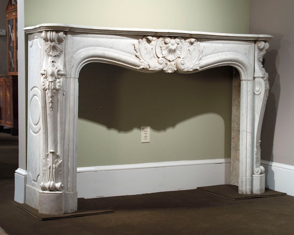 A magnificent Louis XV-style mantel features fine craftsmanship, echoing the luxuriousness of the Louis XV period. The pure beauty of the Carrara marble, combined with the enormous expense involved in obtaining the precious material, makes this a