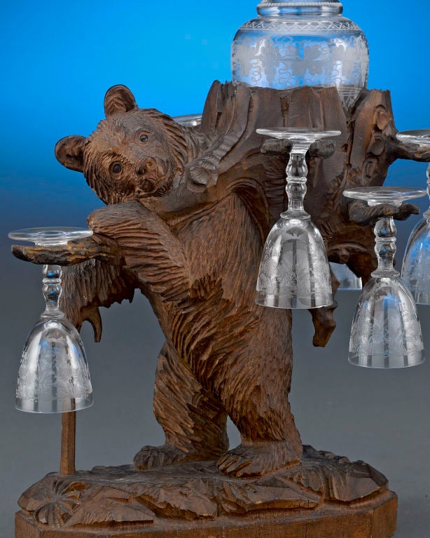 Whimsical subject and detailed carving distinguish this lovely Swiss Black Forest cavé liqueur. This bear, with cane in hand and pack on its back, holds a cut glass decanter and six matching cordials. Originating in Switzerland, Black Forest design