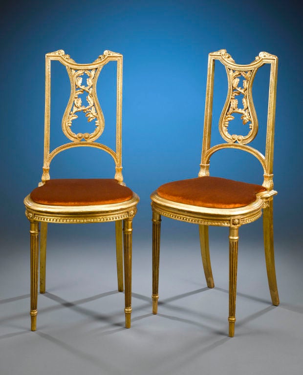 Elegance and refinement distinguish this pair of Louis XVI-style hall chairs. The chairs' straightforward design elements, which include delicate beaded edging and fine, reeded arrow feet, reflect the influence of neoclassical tastes on this