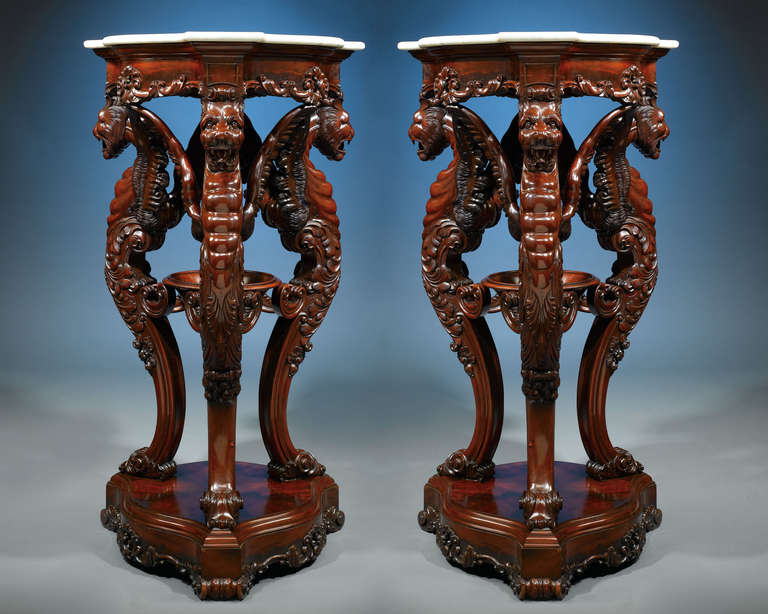 This pair of striking Irish rosewood pedestals with marble tops stand well above four feet tall, making a truly grand statement. The rich rosewood is lavishly carved with dramatic scrollwork and three exotic winged lion supports. These lions each