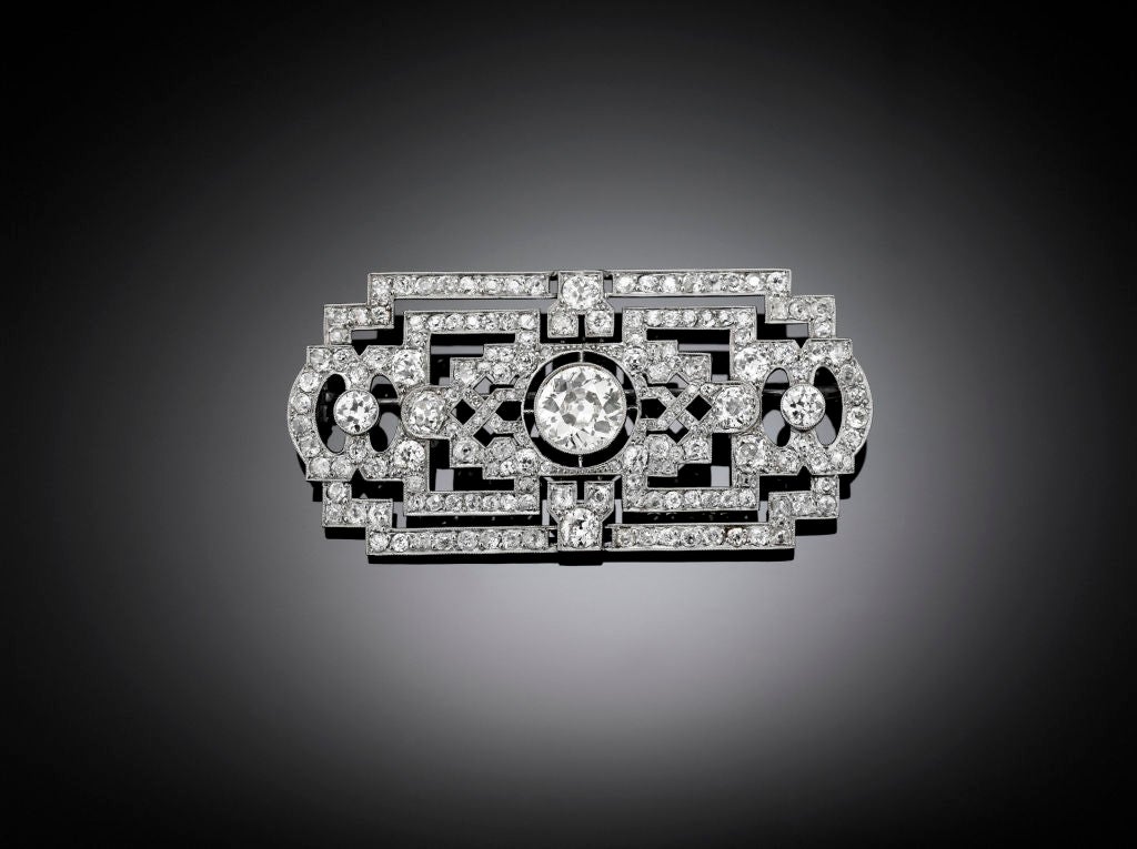 This period Art Deco platinum brooch radiates with approximately 16.25 total carats of Old Mine and European-cut diamonds. These sparkling gems are set within the brooches geometric openwork design, which centers around the bezel-set European-cut