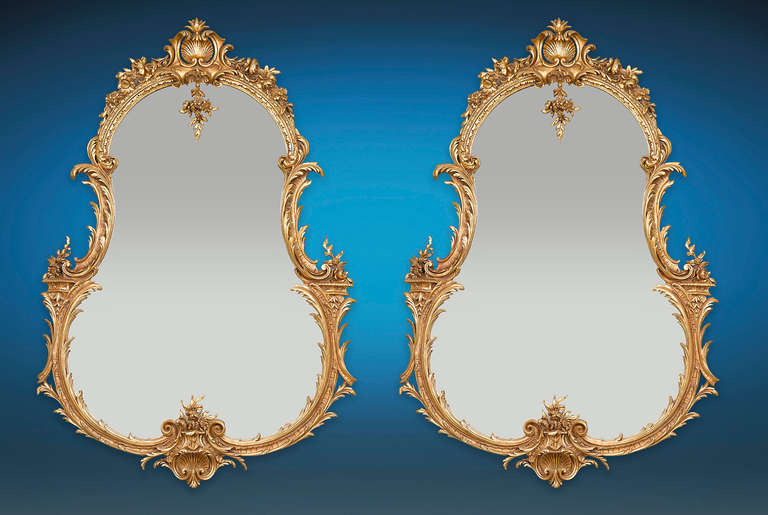 A golden motif of acanthus encircles this opulent pair of Louis XV-inspired mirrors. Each looking glass features an elegant pear shape and an undulating, intricately carved giltwood frame. This mirror is a study in Rococo splendor, with their