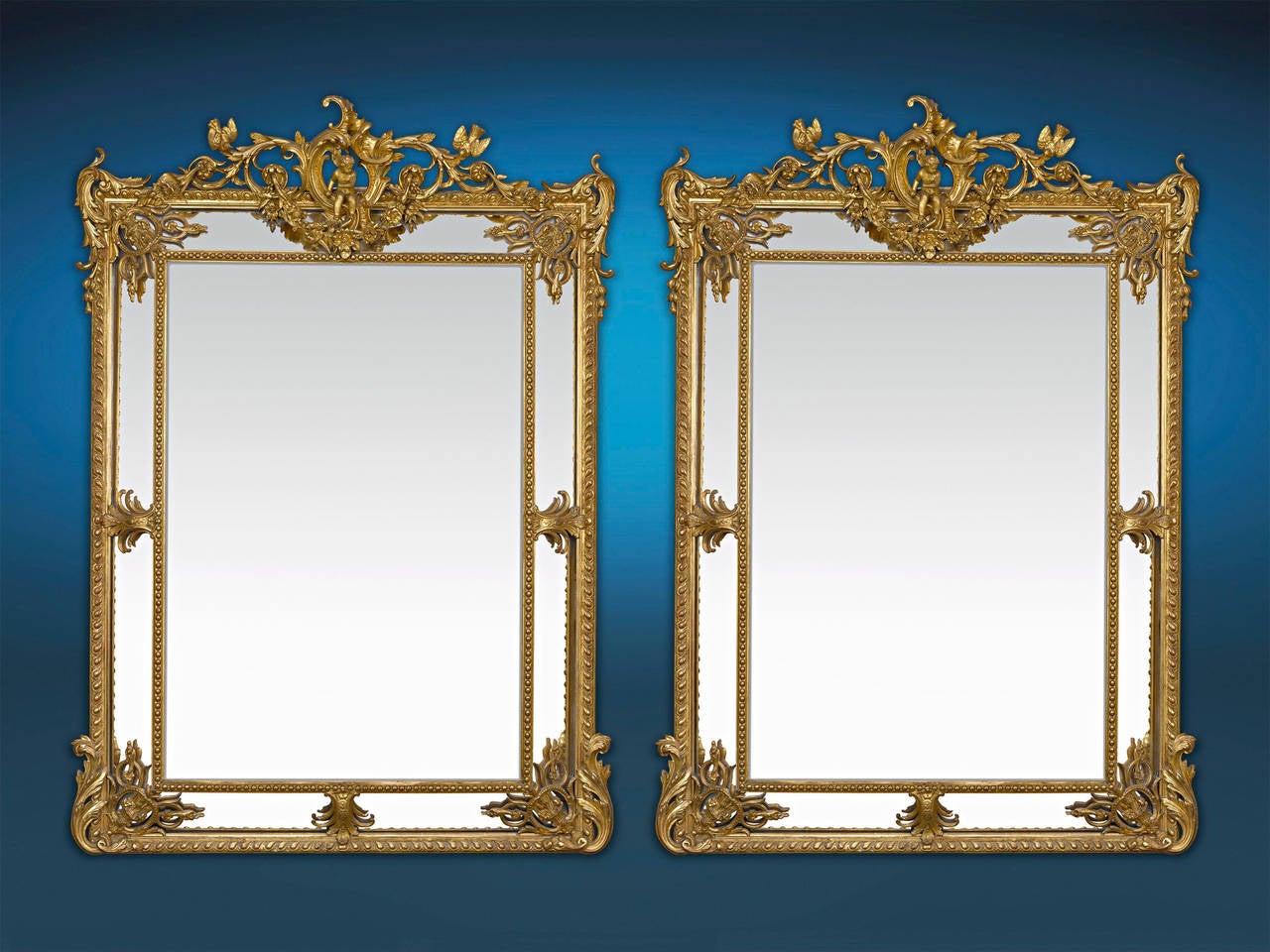 This phenomenal pair of Louis XV-style French mirrors feature elegant, intricately carved giltwood frames. These mirrors are a study in Rococo glamour, with its asymmetrical, foliate decoration, C-scrolls and cherub and bird accents. Highly unique
