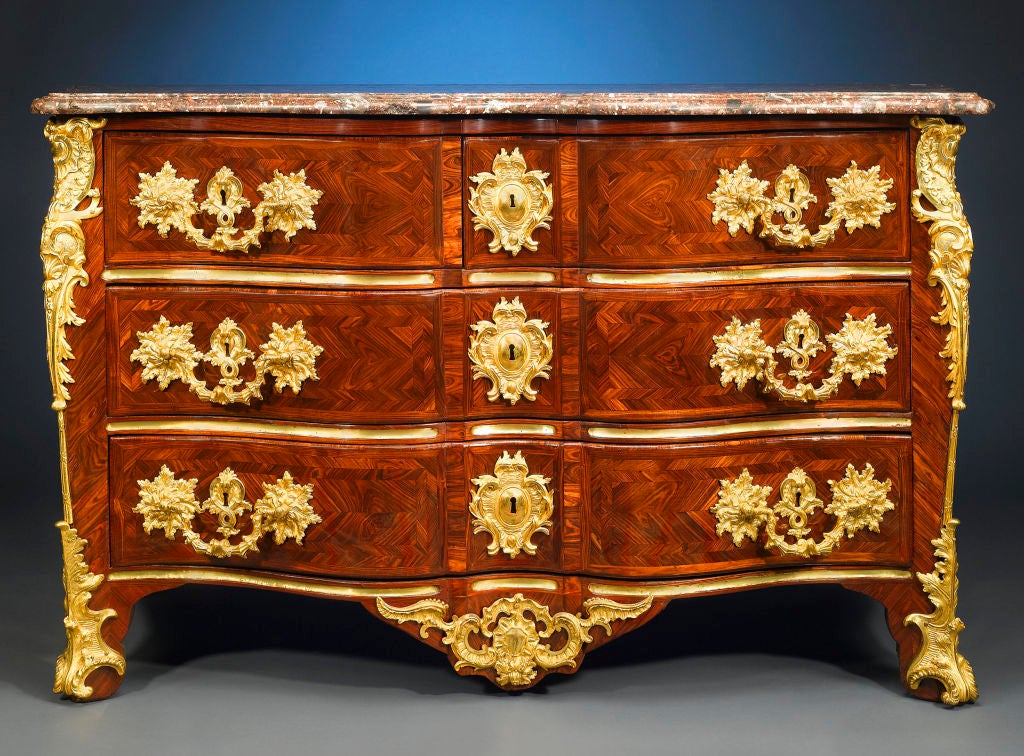 A stunning specimen of the ébéniste’s craft, this important Régence-period arbalète commode, named so for its desirable “crossbow” shape, is veneered in beautiful violet wood and mounted with chiseled mercury-gilded bronze of exceptional quality.