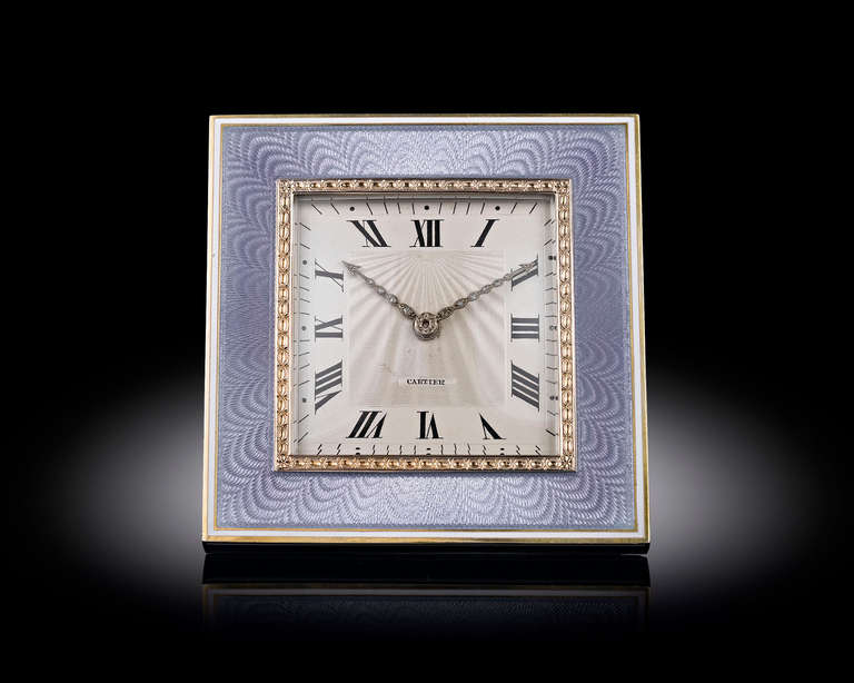 This elegant Art Deco-period desk clock by Cartier features a soft blue guilloché enamel and gold frame studded with four sapphire cabochons. With Roman numerals marking the hours, the dial's radiant guilloché pattern is well-complemented by hands