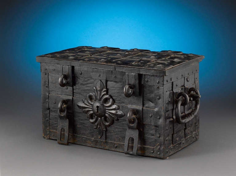 This German strong-box from the1st half of 18th century has a rectangular sheet iron body with riveted iron strap fittings. At the front of the box there is a false keyhole with chased escutcheon and at the sides, two hasps for padlocks. The hinged