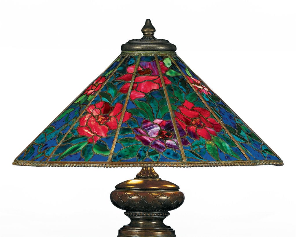 This early and extremely rare table lamp by Tiffany Studios, in the exceptional Peony pattern, is monumental in size, with one of the largest shades ever created by this celebrated firm. Glorious red blooms and verdant leaves set against a deep,