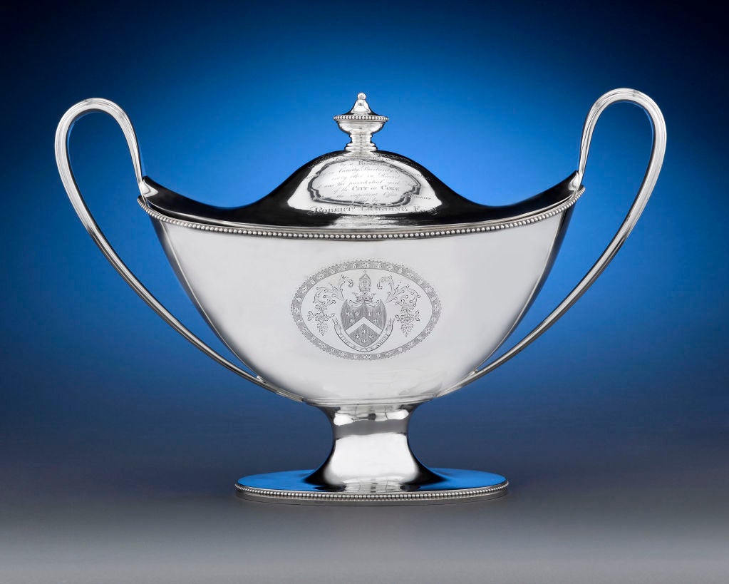 Hester Bateman Geo III Silver Soup Tureen and Cover, London, 1787. Boat-shaped and on spreading base with beaded border, with two reeded scroll handles, the detachable cover with beaded vase finial, the body engraved with two coats-of-arms within