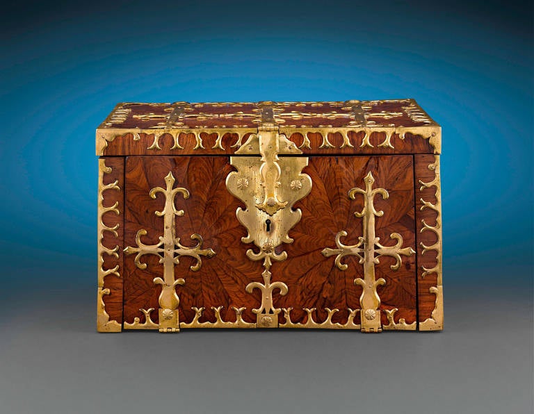This fascinating and rare British lock box boasts exceptional age and condition. Crafted from a gorgeous walnut veneer in an attractive oyster cut pattern, the box is secured by eye-catching decorative reinforcing brass bands. The front of the box