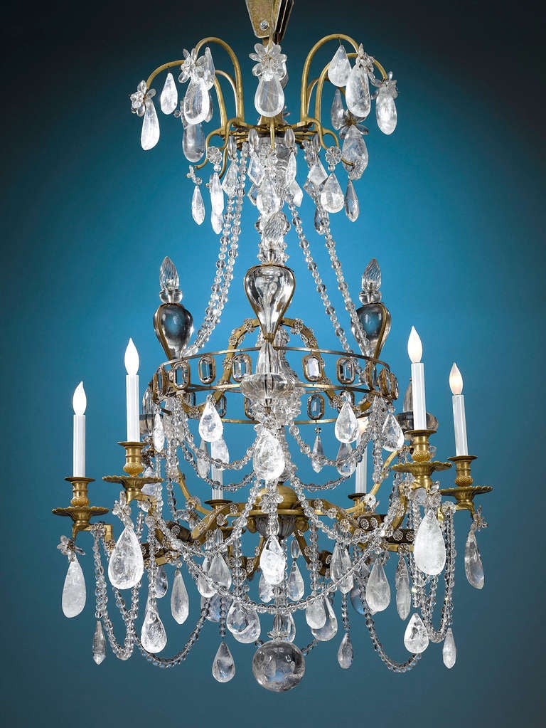 Supported by doré bronze, this chandelier is literally dripping with polished pendants of luminous rock crystal and dressed with crisscrossed beaded rock crystal lines à lace, providing a dispersion and richness of light unmatched by more