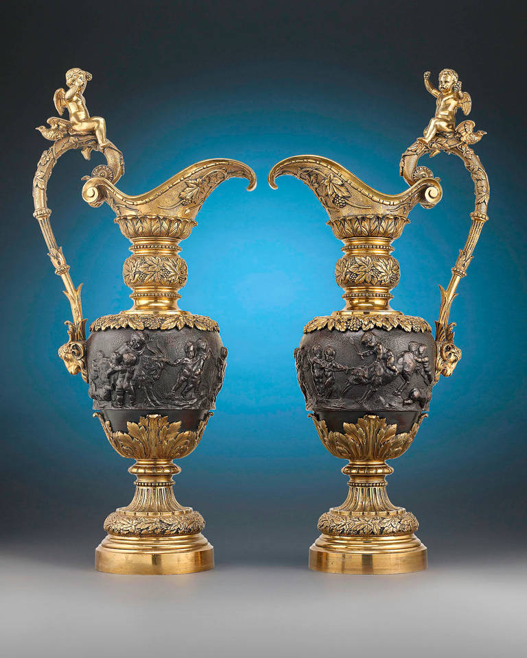 This extraordinary pair of monumental bronze ewers are masterpieces of the Renaissance Revival style and a delightful celebration of Dionysian decadence. A bacchanal scene adorns the patinated midsection of the gilt ewers, presenting a festive motif