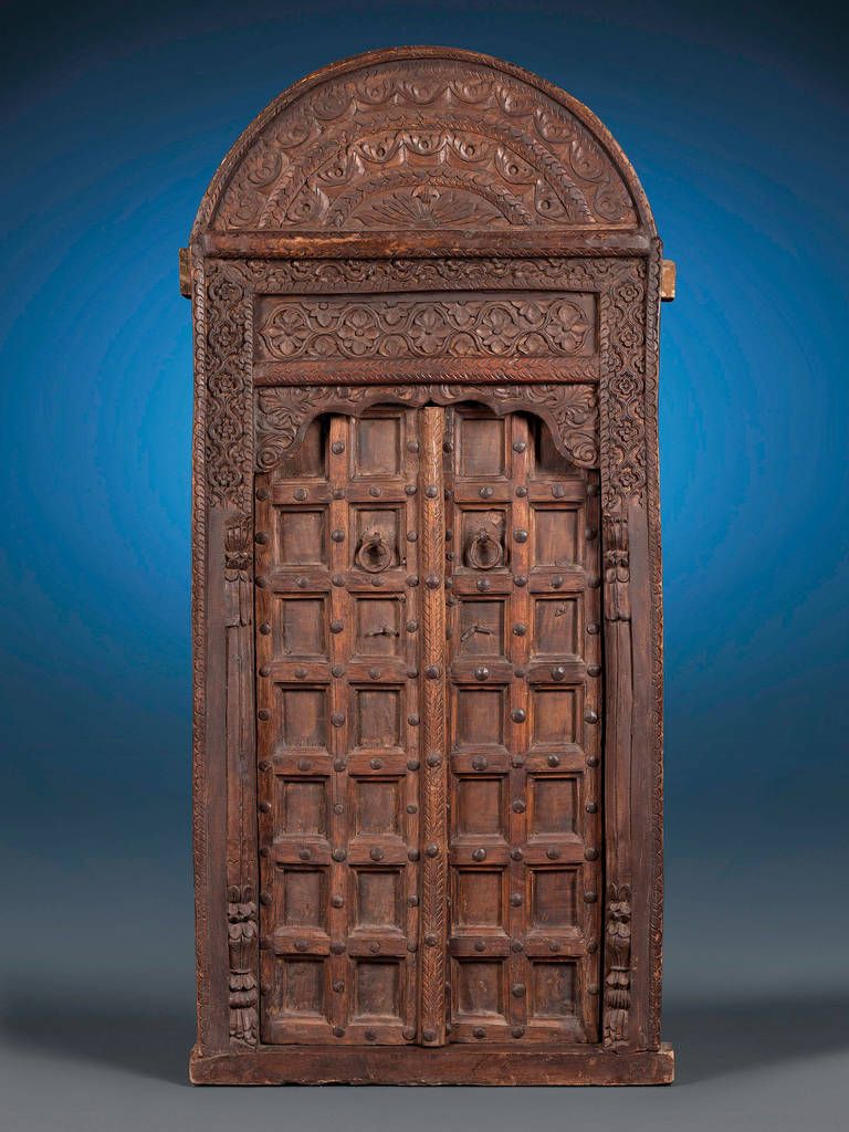 This incredible 16th-century cedar door and frame bears all the distinguishing characteristics of classic Moroccan architecture. The arched structure stands at over six-feet in height and is enveloped in intricate Berber foliate carvings along the