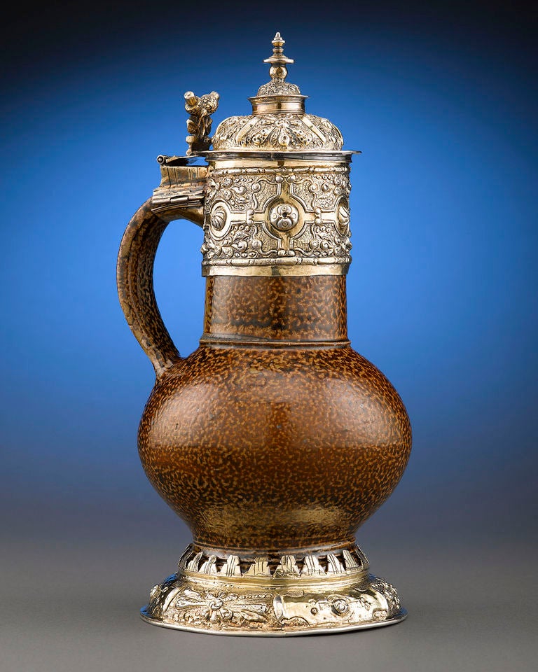 This exceptionally rare silver-gilt mounted tigerware jug was crafted during the Elizabethan period. This handsome vessel is adorned with highly elaborate silver-gilt mounts, including a boldly repousséd hinged lid, which beautifully contrasts the