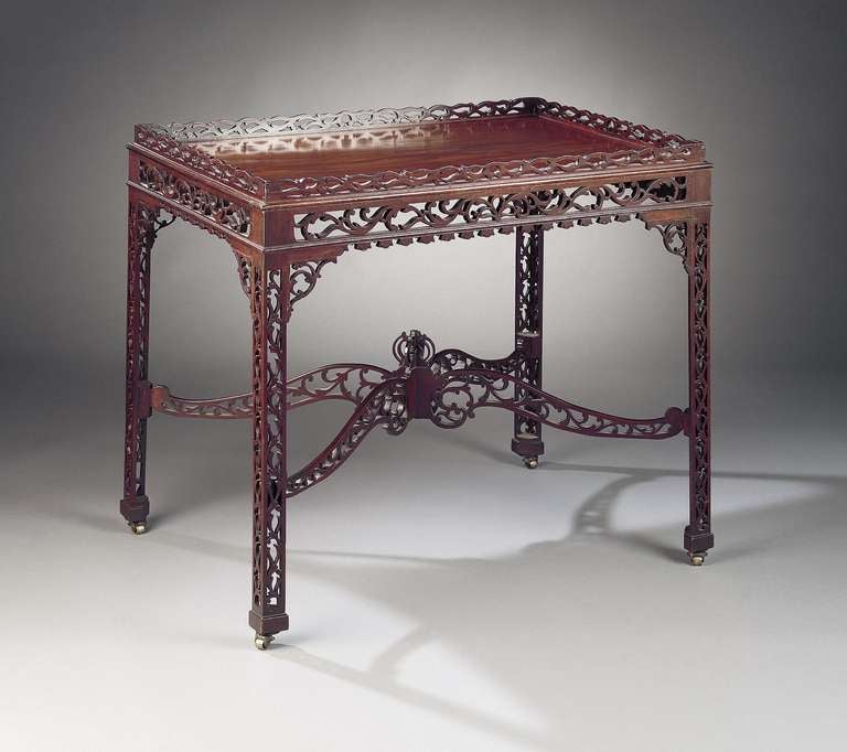 This delightful English mahogany tea table is fashioned in the Chinese Chippendale style and features elaborate fretwork carving. These small, decorative tables are also known as silver or china tables. A similar piece is illustrated in an outline