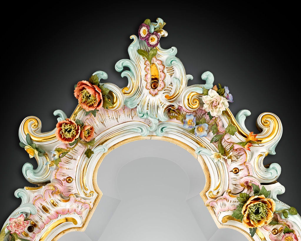 This spectacular Meissen mirror, crafted of the highest quality porcelain, is beautifully decorated in the exuberant Rococo style. Exhibiting a graceful arabesque shape, the mirror is punctuated with stunning, s-and c-curves, shell forms and a