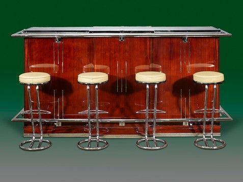 A remarkable mahogany Art Deco bar of exceptional proportion beautifully crafted of polished mahogany mounted with polished chrome accents and a mirrored top. Behind the antique bar is a wonderful, fitted interior with shelves, drawers and a