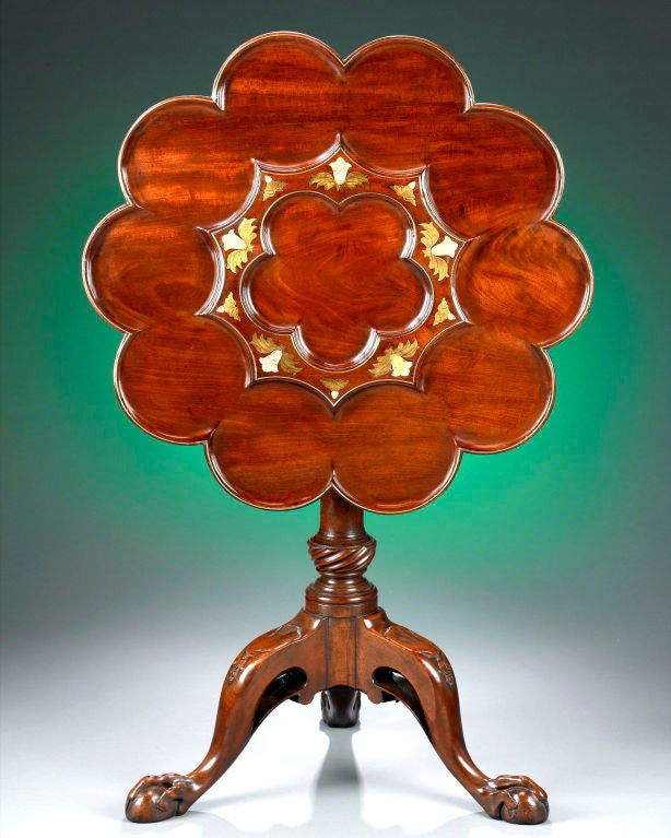 An elegant antique George II mahogany tripod tea table attributed to Frederick Hintz featuring a tilting top enhanced by brass marquetry and mother of pearl inlay. This rare and intriguing table is constructed of rich mahogany with a scalloped-form