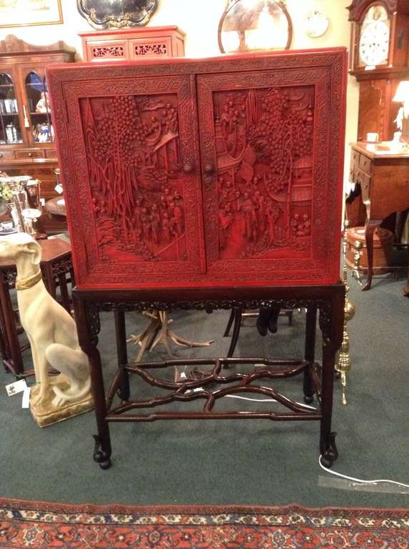 Fabulous Chinese Red Lacquer two door cabinet on carved Rosewood stand. The carving around the edge of the stand is all done by hand. The interior of the cupboard has two shelves which can be totally adjusted up and down the. Slots on both sides.