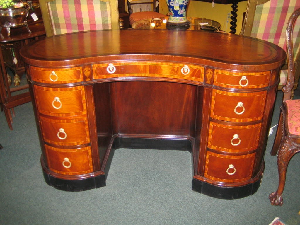 FABULOUS ENGLISH MAHOGANY KIDNEY SHAPED DESK WITH SATINWOOD INLAY AND CROSSBANDING AND STRINGING. THE DESK HAS ITS ORIGINAL BROWN LEATHER TOP WITH GILT TOOLING. ON THE BACK OF THE DESK IS A BUILT IN TWO SECTION BOOKCASE, WHICH IS MOST UNUSUAL.  THIS