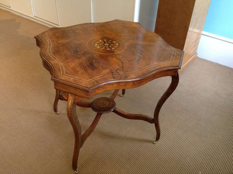 Beautiful English Edwardian Rosewood Side Table inlaid with stringing and a center medallion of exotic woods. The table is also in.aid down the top of each leg and the center medallion on the underneath adjoining the stretchers. The table is a