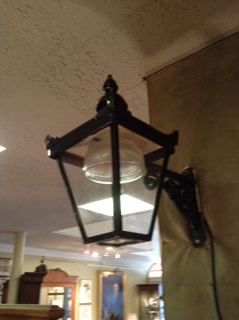 Wonderful English  Antique  Wrought Iron Indoor/Outdoor lantern on wall bracket. The lantern is removable from the bracket for ease of bulb replacement. The lantern is reminiscent of an old English street light. It has the original glass and also a