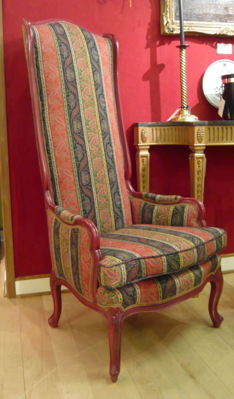 A fabulous pair of dramatic, stylized mid-century bergeres, custom painted in chinese red and newly upholstered in luxurious Ralph Lauren paisley inspired fabric.  These fantastic chairs feature an arched back, loose seat cushion, padded arms, a