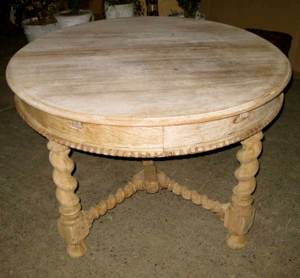This oak dining table has been bleached to this new patina. Note the decorative beading around the center edge of the table and the turned spool legs.