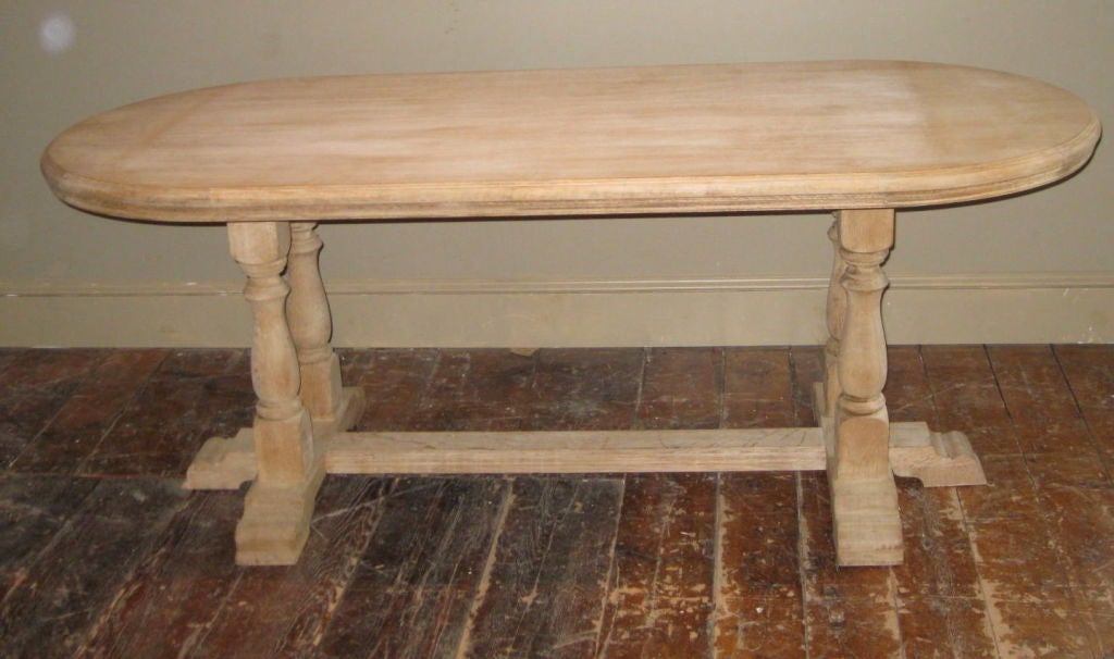 Bleached oak trestle dining table with finial legs.