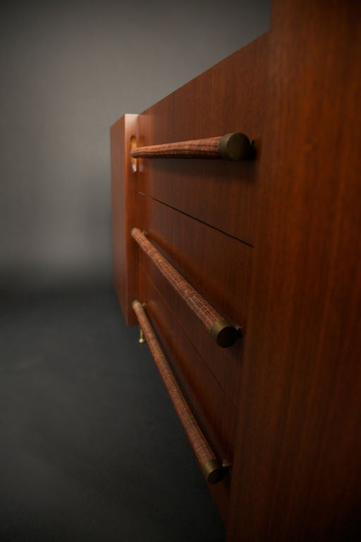 A beautiful and rare example of a buffet or credenza by Robsjohn-Gibbings, designed for Widdicomb, as noted on the early fabric label inside the drawer. Striking delicate brass legs, woven cane handles with brass ends, and the original patina