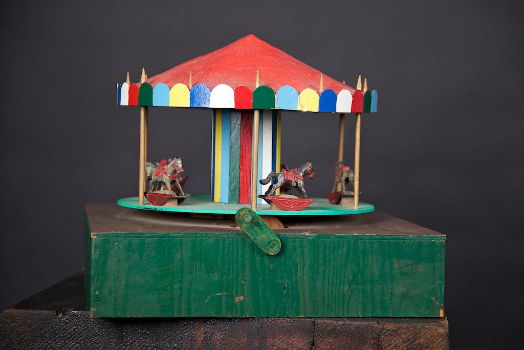 Wooden toy carousel, still in working condition. The metal horses will rock back and forth as the carousel is hand-cranked. This appears to be from the 1930's and is a great example of early American craftsmanship. Base is 16
