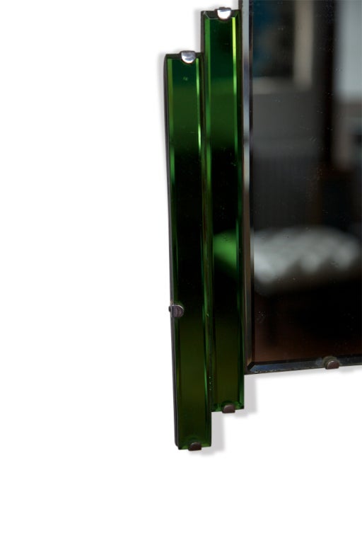 A visually eye-catching, fine example of Art Deco Era mirror, this piece has the original hardware and is very fine condition, especially in light of its age. The green glass and mirror play off each other very well. 

A great accent mirror for a