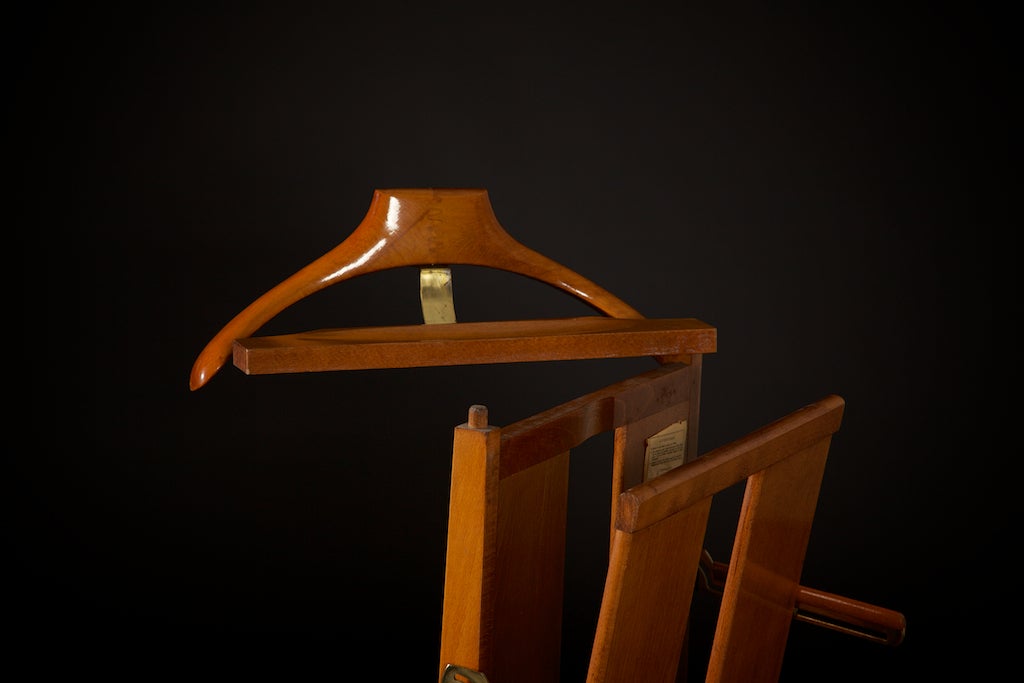 High quality valet stand/butler, with hard-to-find pant press arm. Brass fittings including casters; this is nicely designed in walnut, with a tie clip/cuff links tray on top, and a rich, warm patina throughout. Has original designer markings and