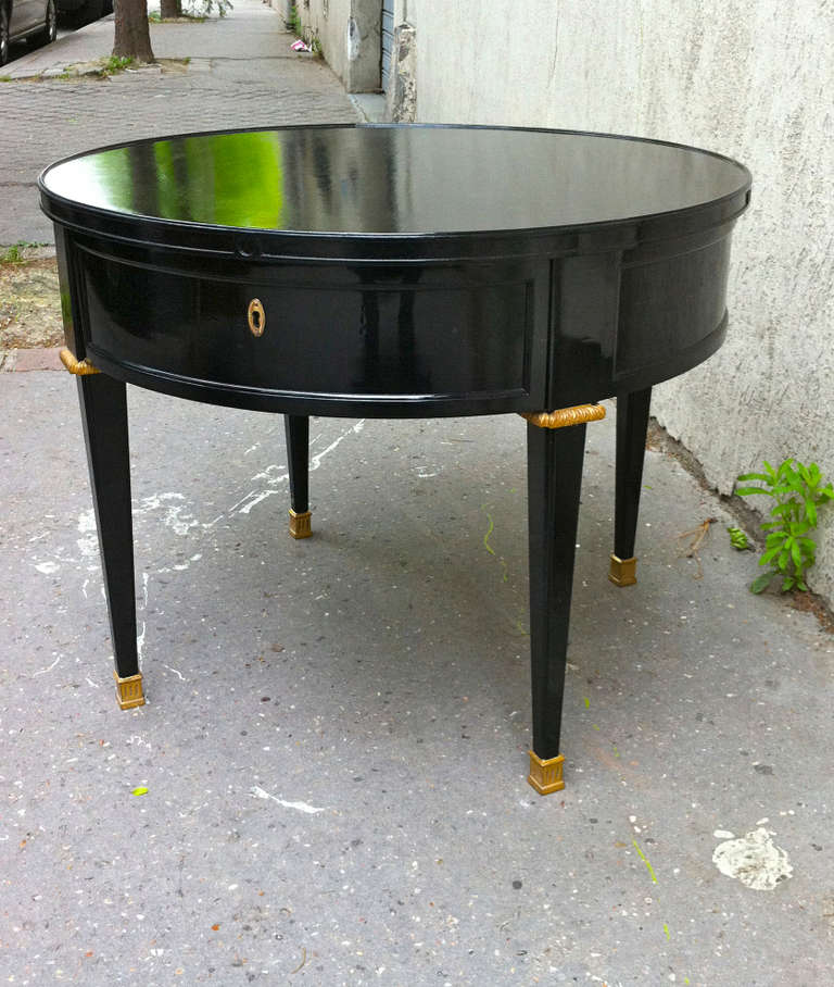 Stamped Jansen one-drawer black lacquered table with gold bronze hardware.