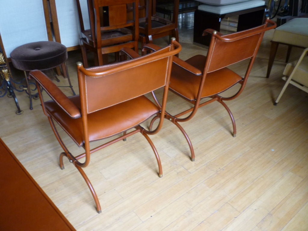 Exceptional pair of semicircle legged armchairs by Jacques Adnet in hand-stitched brown leather.
  