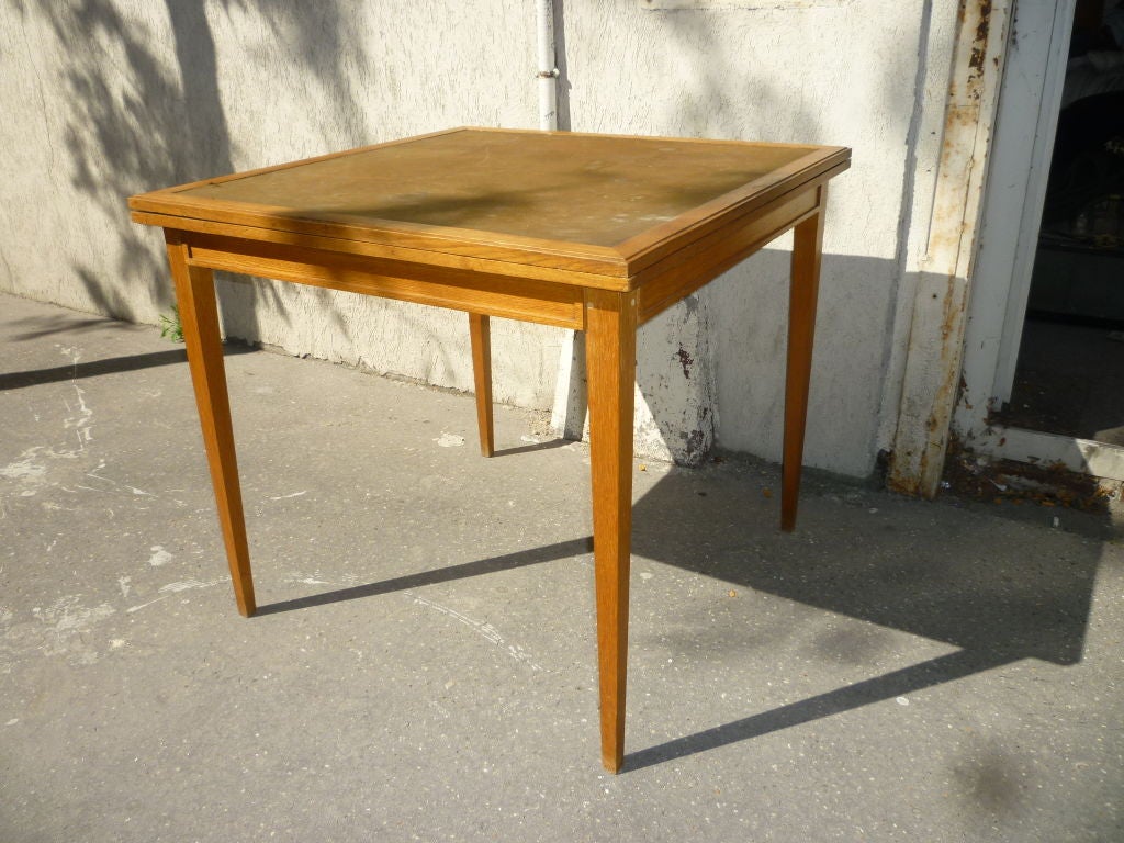 Very pure neoclassic oak playing card table by Jacques Adnet that can unfold into
an additional dinning table.