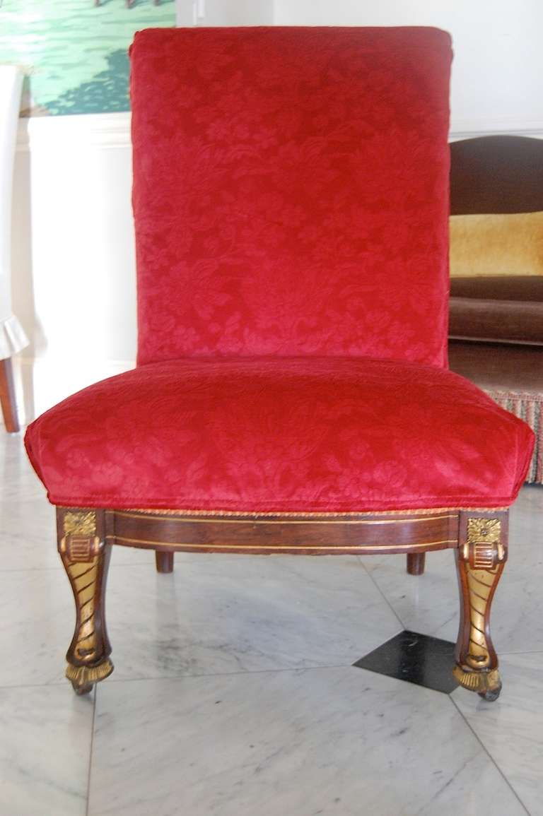 Museum quality early 19th century American rosewood and parcel-gilt slipper chair. Elaborate detailing on front legs terminating in cloven hooves. Presently slipcovered in red silk velvet. The original upholstery is in excellent condition, but the