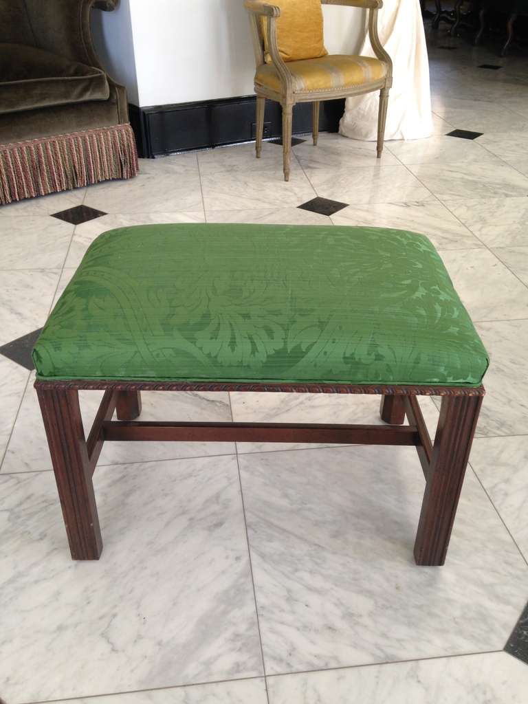 Elegantly simple, mahogany Chippendale style stool with straight reeded legs, a T stretcher and a decorative carving at seat base. Newly re-upholstered in Fine green silk brocade.