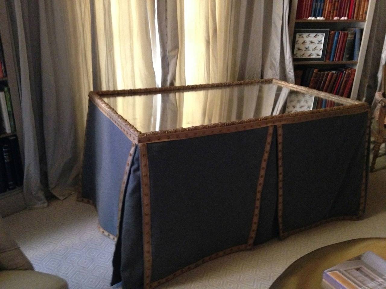 19th century French mirror with old glass and gold leaf frame forms the top of this purpose-built custom dressing table. The fabric skirt is lined grey wool with Samuel and Sons gold braid edging. There are knife pleats in the center and at the